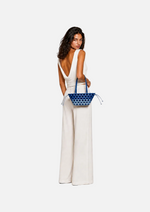 Load image into Gallery viewer, Woman holding a blue handbag against a gray background